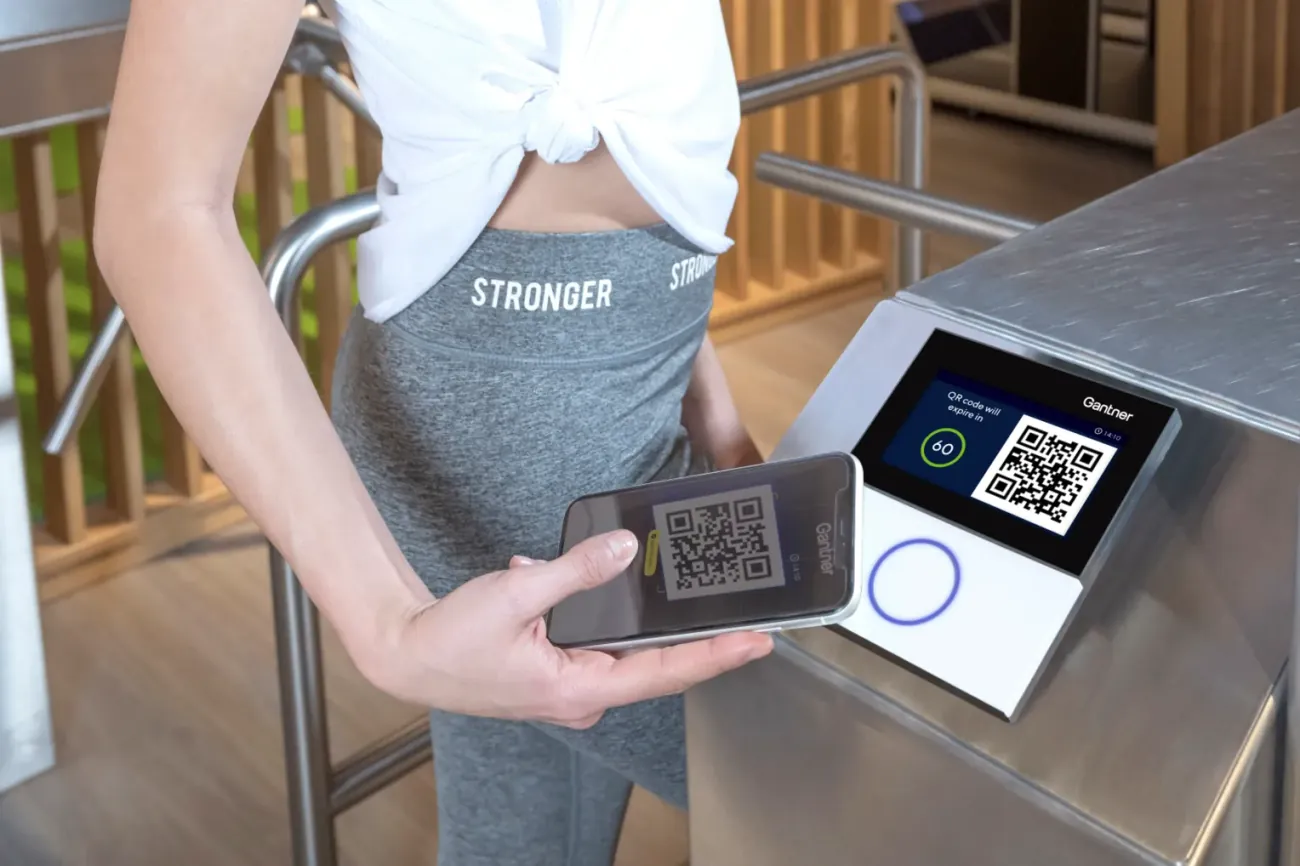 A member scans a QR code on their phone to enter through the turnstile