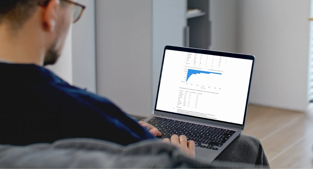 A person at a laptop showing a report with a bar chart and a data table