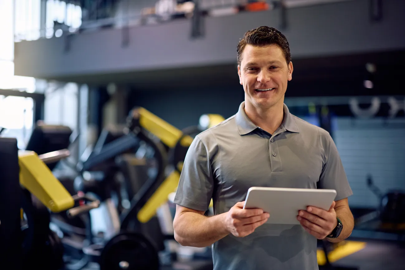 A gym operator checks live numbers on a tablet while walking the training floor.