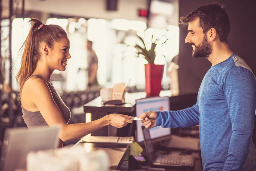 Member checking in with a receptionist at a gym front desk