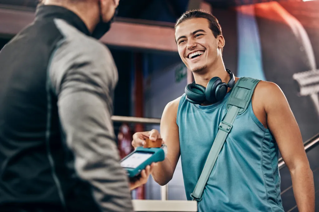 Member paying at a card terminal at the gym front desk