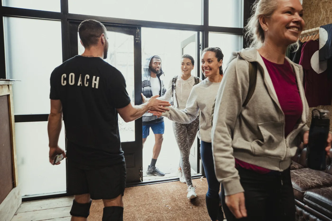 A coach high-fives members as a group arrives for class at the studio entrance