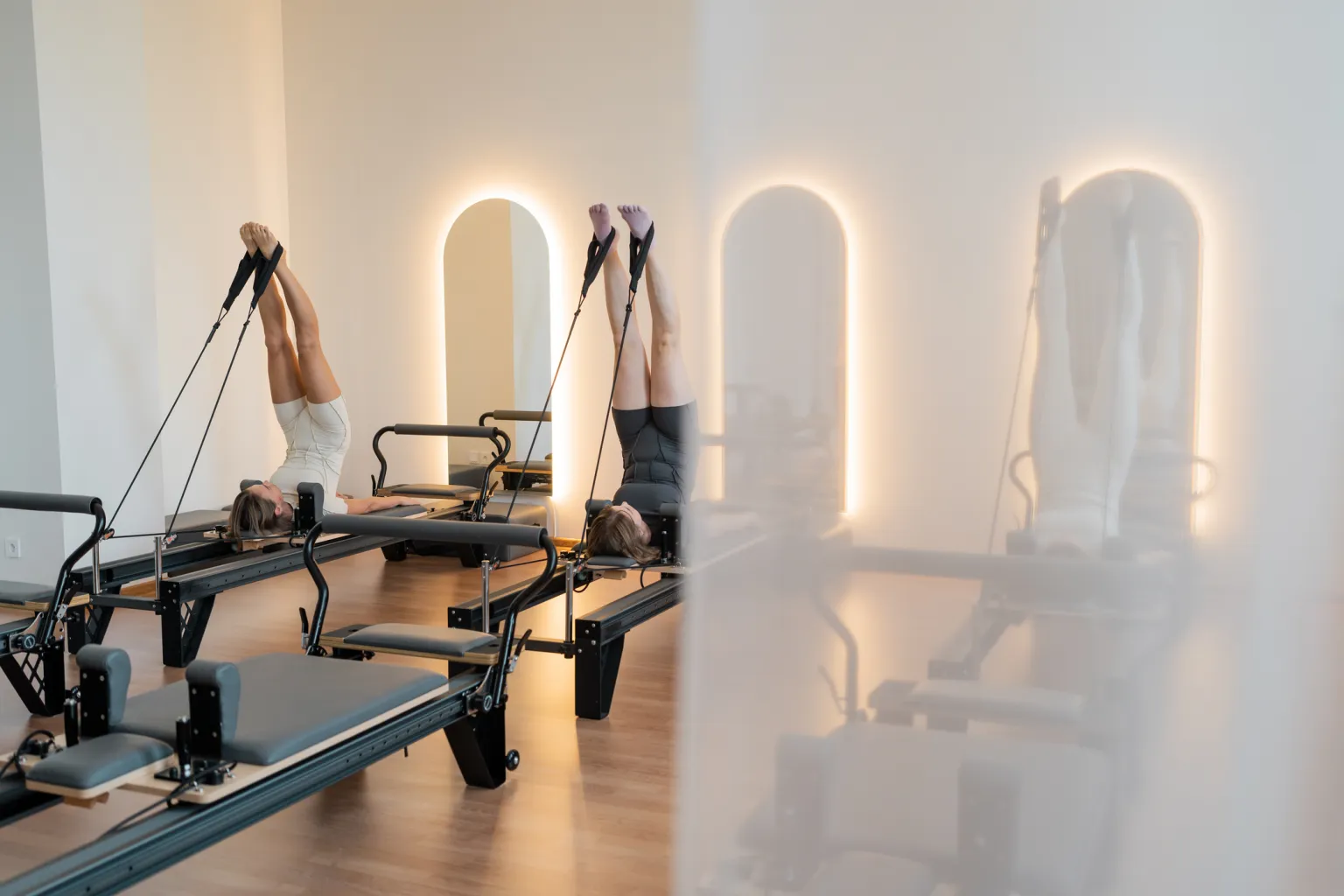Members mid-exercise on reformers in a boutique Pilates studio